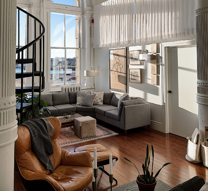 Sun filled lounge room with grey sofa and brown armchair